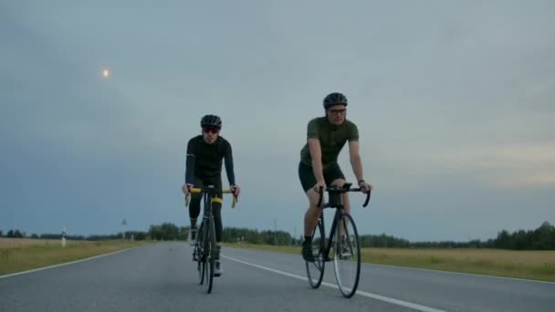 Två passar cyklister tävla mot varandra på vägen. — Stockvideo