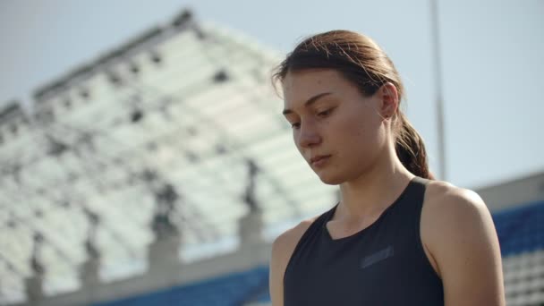 Vacker kvinna idrottare på arenan andas och förbereder sig för att starta loppet. Motivation och stämning för loppet. Koncentration och attityd. — Stockvideo