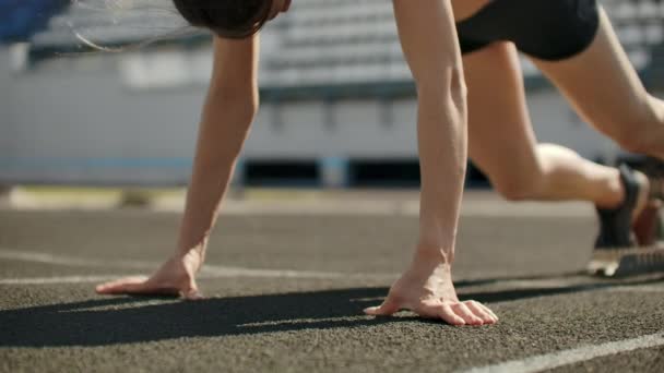 Slank jong meisje atleet is in staat om de begint te lopen in de pads op het spoor in slow motion. — Stockvideo