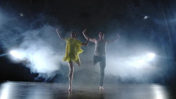 Un par de bailarines en el escenario en humo y proyectores moviéndose rápido — Vídeos de Stock