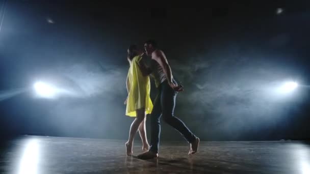 Un par de bailarines en el escenario en humo y proyectores moviéndose rápido — Vídeos de Stock