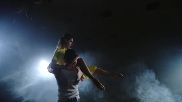 Пара танцующих на сцене в прожекторах и дыму — стоковое видео