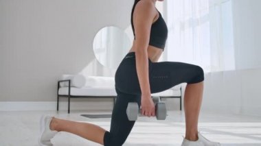 genç fit ve enerjik kadın güneşli bir gün boyunca evde oturma odasında sağlıklı yaşam tarzı için ağırlıkları ile spor egzersiz ve fitness lunge egzersizleri yapıyor.