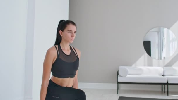 Молодая и энергичная женщина, занимающаяся спортивными упражнениями и упражнениями для выпадов с гирями для здорового образа жизни в гостиной дома в солнечный день . — стоковое видео