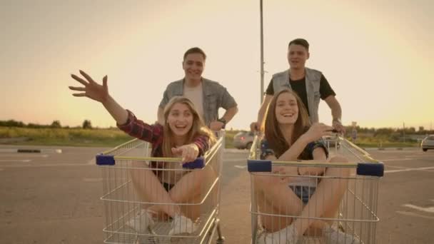 Young friends having fun on a shopping carts. Multiethnic young people playing with shopping cart. — Stock Video