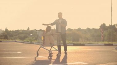 Alışveriş arabalarında eğlenen genç arkadaşlar. Çok ırklı gençler alışveriş sepetinde yarışıyor. yavaş çekim.