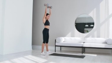 Güçlü ve Fit Güzel Kız Atletik Top Minimalist İç ile Onu Parlak ve Geniş Oturma Odasında Squat Egzersizleri yapıyor.