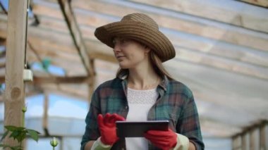 Azgın güzel kız işadamı çiçekçi bir tablet bilgisayar ile sera ile yürür yetiştirilen gül kontrol eder, hasat takip eder ve çiçek iş müşterileri sunmak için planlar.