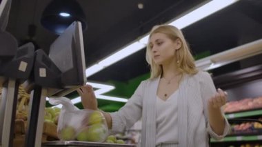 Elektronik Terazide Elma Ları Tartıp Alan Genç Kadın. Meyve ve Sebze Bölümü'nde Bir Süpermarkette Ev Hanımı Alışveriş. Yavaş Çekim. Satış, Alışveriş, Tüketicilik ve İnsanlar Kavramı.