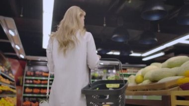  Geri görünümü Bakkal sepet alışveriş ile Genç ev kadını. Sevimli kız bakkal bölümüne gider ve sepete koyar. Konsept satın alma, alışveriş, reklam, alıcı, ürün, fırın.