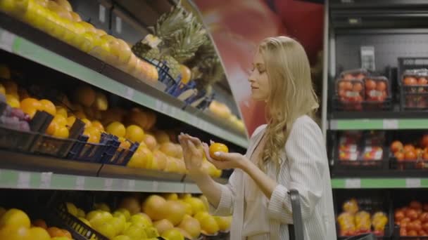 Zeitlupe Mädchen wählt Mandarinen legt in Tüte. Zeitlupe close view Mädchen Hand wählt frische aromatische Mandarinen und in Plastiktüten gegen Boxen. — Stockvideo