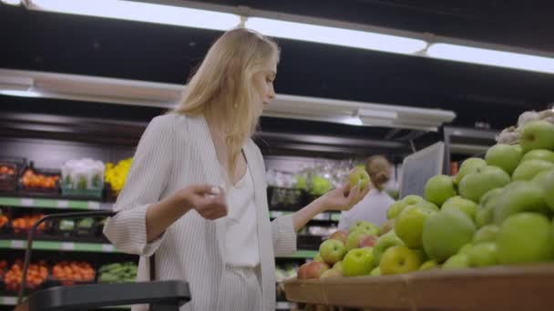 果物野菜のスーパー マーケットでリンゴを選択する魅力的な若い女性. — ストック動画