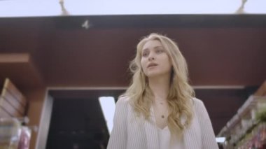 Sepetli bir markette bir kadın alıcı raflar ve tezgahlar arasında mal ve ürünler, bir süpermarkette bir kadın bakarak yürür.