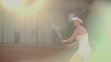 Kortta kadın tenisçi uçan bir topa vurur, açık kortta tenis dinamik bir oyun.