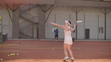 Tenis kortundaki kadın tenisçi raketle ve gün batımında yavaş çekimde tenis oynuyor