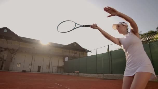 Тенісна гра в сонячний день на тенісному корті молода спортивна жінка грає в професійний теніс. Професійний тенісист потрапляє в м'яч — стокове відео