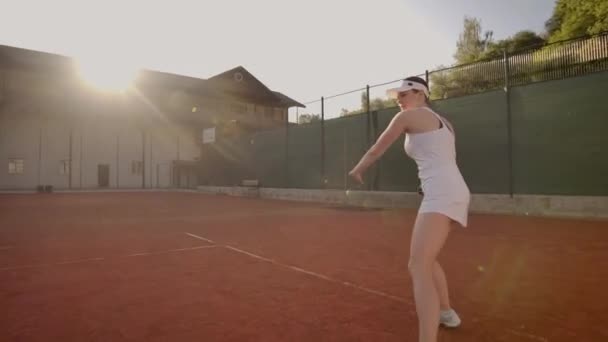 Juego de tenis en el día soleado en la cancha de tenis joven mujer deportiva jugando tenis profesional. Jugador de tenis profesional golpea la pelota — Vídeos de Stock