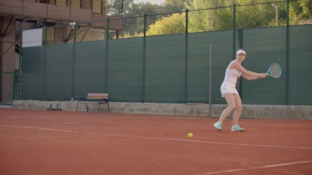 Professionell ausgestattete Frau schlägt hart den Tennisball mit Tennisschläger. Professionell ausgestattete Frau schlägt mit Tennisschläger hart auf den Tennisball.