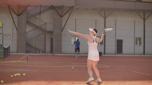 Kvinna tennisspelare på tennisbana spela tennis i slow motion med racket och vid solnedgången — Stockvideo