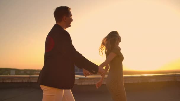 Mladý pár drží ruce chodící ženu, která vede přítele, střechu budovy při západu slunce POV cestování. Bezstarostní svobodní milenci běží na střeše a usmívají se. — Stock video
