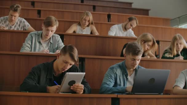 大批多民族学生在现代课堂上听讲座时, 在笔记本电脑上工作。明亮的年轻人在大学学习 — 图库视频影像