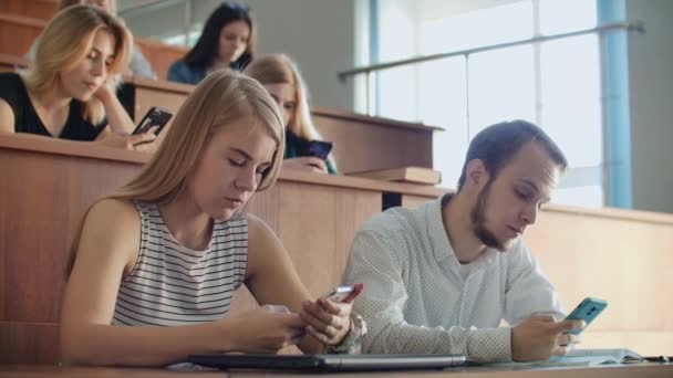 Многонациональная группа студентов с помощью лекций. Молодые люди используют социальные медиа во время учебы в университете . — стоковое видео