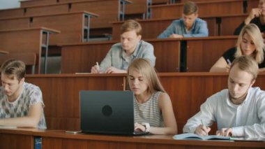 Çok etnik öğrencilerin çalışma Modern sınıfta bir ders dinleme sırasında dizüstü bilgisayarlarda büyük grup. Üniversitesi'nde çalışma parlak gençler