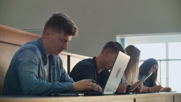 Grande grupo de estudantes multi étnicos que trabalham nos laptops enquanto ouvem uma palestra na sala de aula moderna. Jovens brilhantes estudam na Universidade — Vídeo de Stock