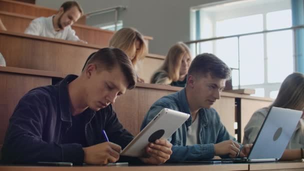 Große Gruppe multiethnischer Studenten, die an ihren Laptops arbeiten, während sie einer Vorlesung im modernen Klassenzimmer lauschen. Junge, kluge Leute studieren an der Universität — Stockvideo