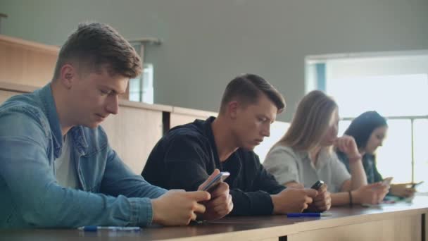 多民族学生在讲座中使用智能手机。在大学学习时使用社交媒体的年轻人. — 图库视频影像