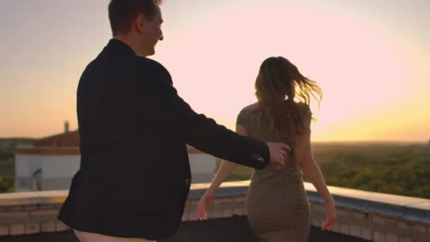 Jeune couple tenant la main femme marchant petit ami leader le toit de l'immeuble au coucher du soleil POV concept de voyage. Amoureux insouciants courir sur le toit riant et souriant . — Video