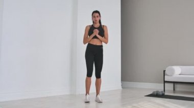 Neşeli sportif kadın yan hamle yapıyor. Orta yaşlı mutlu sporcu oturma odası yan lunges yapıyor ve ileri ye doğru gülümseyerek eğitim sırasında.