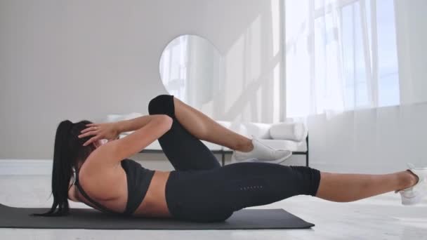 Chica joven haciendo ejercicios de crunches de bicicleta, haciendo ejercicio en casa. Chica de fitness joven haciendo ejercicios de bicicleta intensivos fáciles en casa tumbado en el suelo, deportivo . — Vídeo de stock