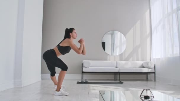 Mujer deportiva alegre haciendo embestidas laterales. Mediana edad feliz deportista sala de estar haciendo embestidas laterales y sonriendo hacia adelante mientras se entrena . — Vídeos de Stock