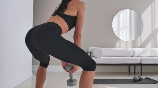 Jonge fitness vrouw doet Squat met dumbbells in handen — Stockvideo