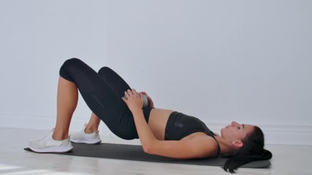 Spor giyimli kadın kalça köprüsü egzersizi yapıyor. Neşeli çekici genç kadın oturma odasında yerde yatan ve kalça köprü egzersiz yapıyor. — Stok video