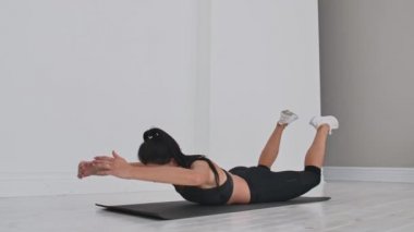 Çift Bacak Kicks egzersiz genç çekici kadın, gri stüdyo. Genç çekici kadın yoga, Çift Bacak Kicks egzersiz germe.