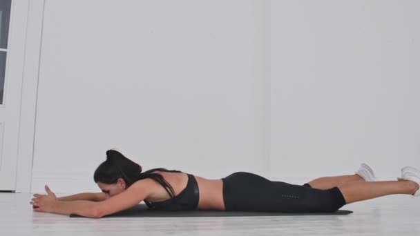 Ung attraktiv kvinna i dubbel ben sparkar övning, grå Studio. Ung attraktiv kvinna tränar yoga, stretching i dubbel ben sparkar övning. — Stockvideo