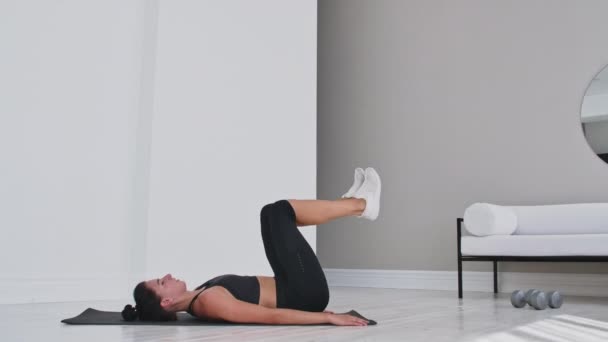 Entraînement de force poids corporel entraînement femme athlète faisant Flutter Kicks. Européen femme adulte faire des exercices au sol avec jambe soulève pour exercer abdominaux muscles à la maison dans son appartement . — Video