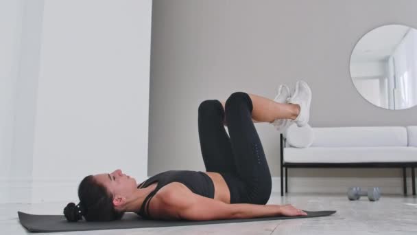 Allenamento di forza peso corporeo atleta donna che fa Flutter Kicks. Europeo femmina adulto fare pavimento esercizi con gamba solleva per esercitare addominali muscoli a casa nel suo appartamento . — Video Stock