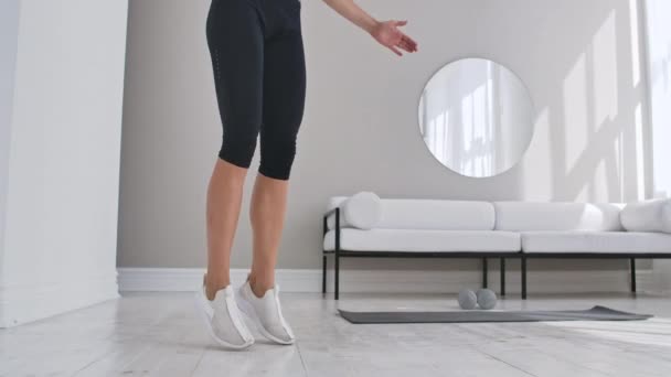 Una donna che fa salti mortali a casa. Sportswoman facendo salto jack esercizio a casa . — Video Stock