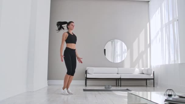 Vrouw doet Jumping Jacks thuis. Sportswoman doen Jumping Jacks oefening thuis. — Stockvideo