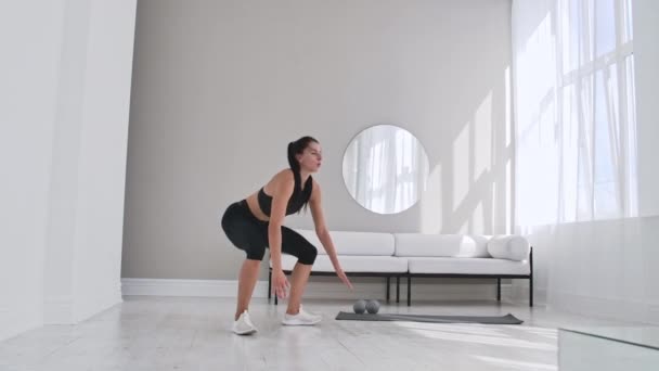 Schöne schlanke Frau in den Dreißigern mit hellem Teint macht morgendliche Kraft- und Aerobic-Burpee-Übungen in einem modernen, luftigen Raum. — Stockvideo