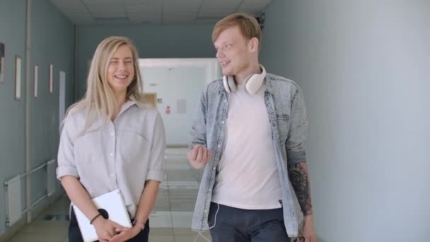 Een man en een meisje lopen langs de College corridor en lachen en praten — Stockvideo