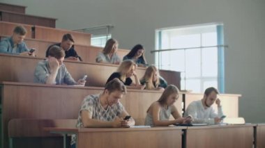Üniversitede sıkıcı bir ders, öğrenciler akıllı telefonlar ekranlarına bakmak. Birçok kişi