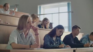 Bir profesörden üniversitede ders dinleyen bir grup öğrenci. Kolej dersleri için geniş hedef kitle