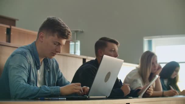 Student använder laptop för att spela in föreläsningar i klassen med studenter. — Stockvideo