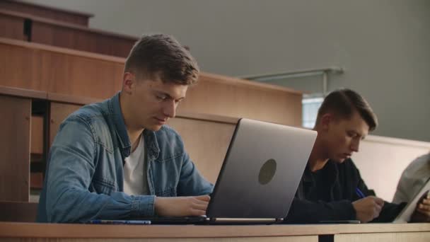 Studenten aan een universiteit of hogeschool schrijven een lezing op een laptop. Afgestudeerd aan het Instituut — Stockvideo