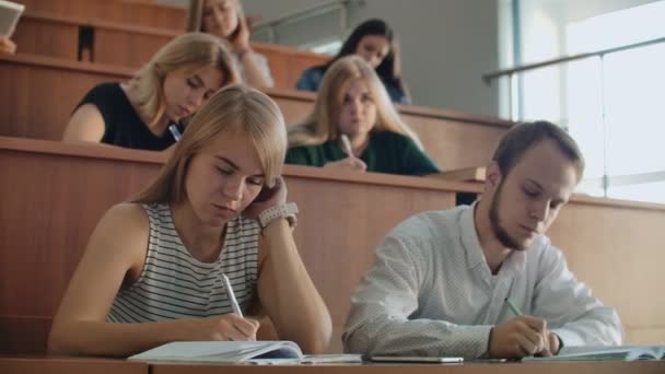 Jovens estudantes de sucesso em uma grande classe universitária ouvir e gravar uma palestra, uma verdadeira palestra na universidade — Vídeo de Stock