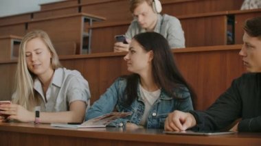Dersten önce bir konferans salonunda oturan neşeli mutlu öğrenciler grubu. Dersten önce bir derssalonunda oturan neşeli öğrencilerden oluşan bir grup